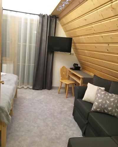 a room with a couch and a desk with a tv at Rezydencja Kojsowka in Witów