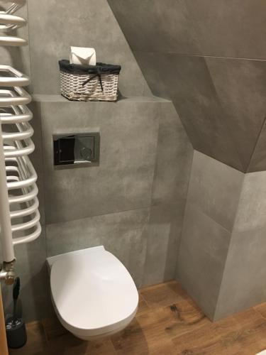 a bathroom with a toilet and a basket on the wall at Rezydencja Kojsowka in Witów