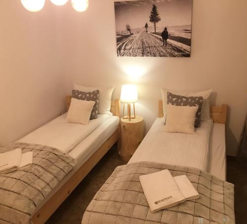 two twin beds in a room with a picture on the wall at Rezydencja Kojsowka in Witów