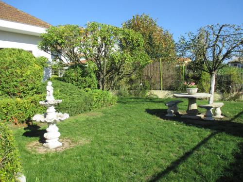 a garden with a table and a fountain in the grass at Les Roses de Rita in Boisset-lès-Montrond
