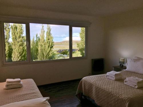 two beds in a room with two windows at Flamenco Bay Apartments in El Calafate