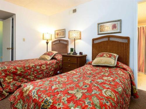 a hotel room with two beds with red blankets at Island Winds East II in Gulf Shores