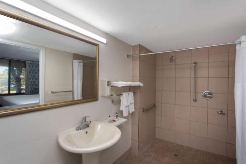ein Bad mit einem Waschbecken und einer Dusche mit einem Spiegel in der Unterkunft Days Inn & Suites by Wyndham Tallahassee Conf Center I-10 in Tallahassee