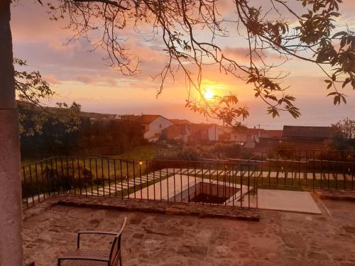 a view of the sunset from a balcony with a bench at Casa do Castanheiro - Nordeste, Açores in Nordeste
