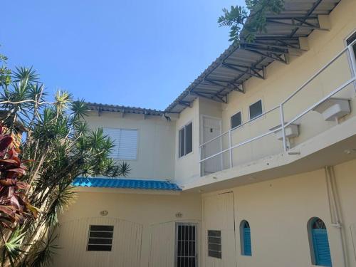 a white building with a balcony and a palm tree at Apartamento beira da Praia das Ondinas in São Lourenço do Sul