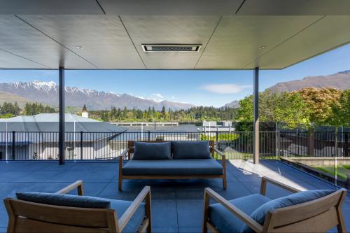 a patio with a couch and chairs and a view of mountains at Waipatiki by Sotheby's Luxury Rental Homes in Queenstown