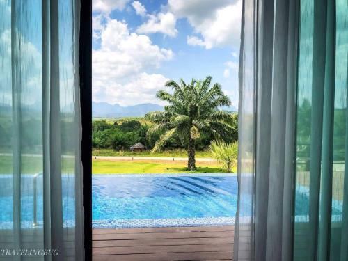 a window with a view of a pool and a palm tree at Belong Jin The Dam Hotel And Resort in Ban Pha Saeng Lang