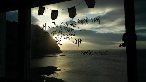 a window with a view of the ocean with writing on it at Nice View Guesthouse in Seogwipo