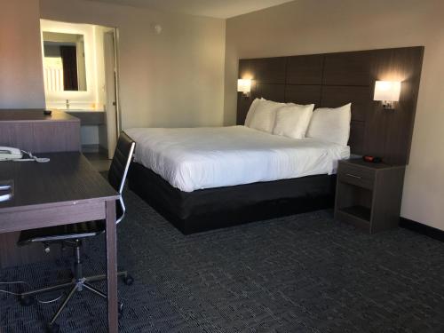 a hotel room with a bed and a desk and a desk at Days Inn & Suites by Wyndham Charleston Airport West in Charleston