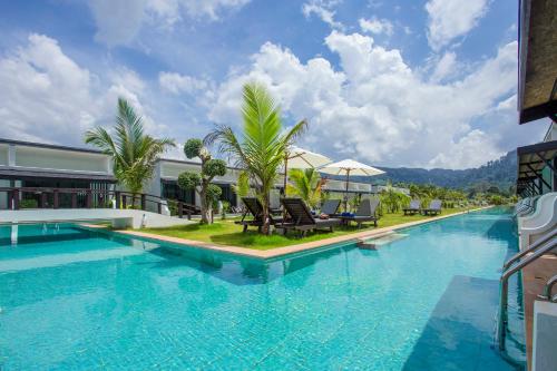 a large swimming pool with chairs and trees next to a building at The La Valle'e Resort in Khao Lak