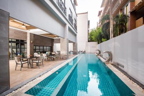 a pool in the middle of a building with tables and chairs at Woovo Phuket Patong - SHA Extra Plus in Patong Beach