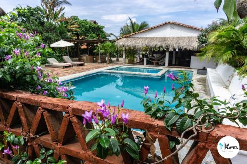 una piscina nel cortile di una casa con fiori viola di La Playita Beach House a Puerto Escondido