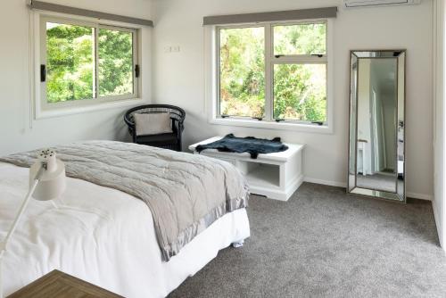 a white bedroom with a bed and a mirror at The House at No 1 in Havelock North