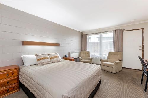 - une chambre avec un grand lit et deux chaises dans l'établissement Admella Motel, à Portland