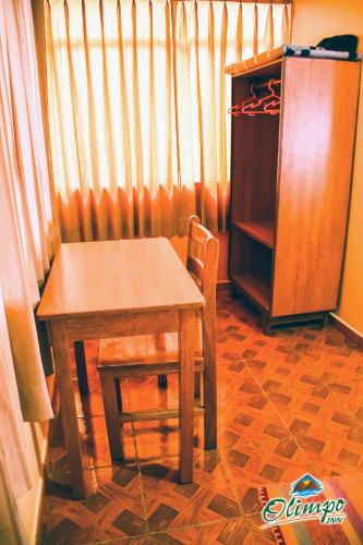 a wooden table and chair in a room with curtains at Olimpo Inn in Puno