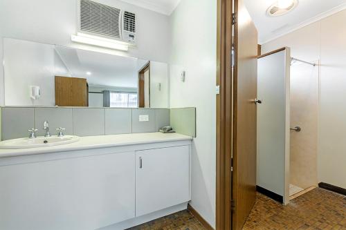 La salle de bains blanche est pourvue d'un lavabo et d'un miroir. dans l'établissement Admella Motel, à Portland
