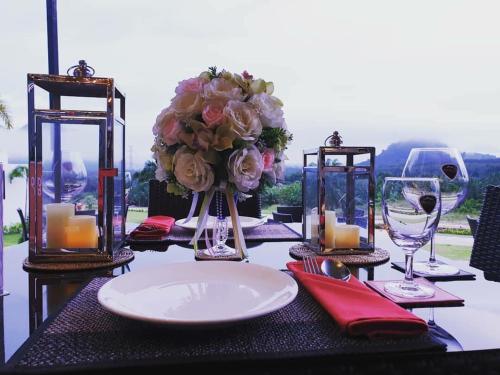 a table with a white plate and flowers and candles at Belong Jin The Dam Hotel And Resort in Ban Pha Saeng Lang