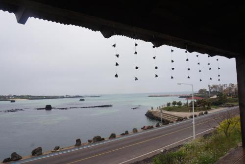 a view of the water and a road with shoes hanging from a building at Africa Guesthouse in Jeju