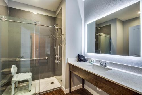 a bathroom with a glass shower and a sink at Scottish Inns & Suites Houston, TX in Houston