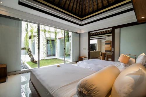 a bedroom with two beds and a large window at Kedonganan Beach Villas in Jimbaran