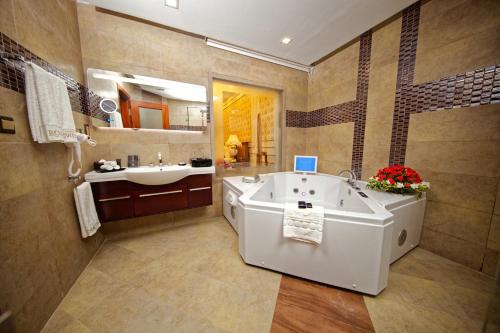 a bathroom with a large tub and a sink at Royal Swiss Lahore in Lahore
