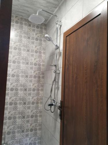 La salle de bains est pourvue d'une douche et d'une porte en bois. dans l'établissement Студио Теа, à Sliven