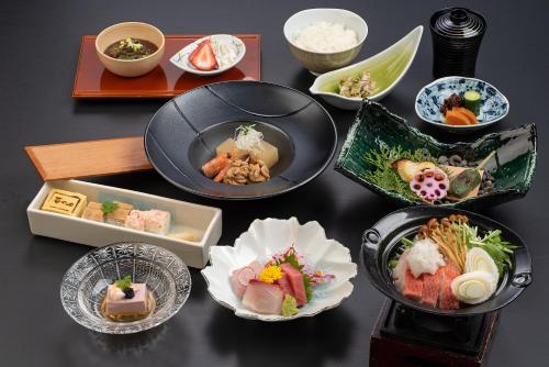 a table topped with plates of sushi and other dishes at Ishinoya Izunagaoka - TKP Hotels & Resorts in Izunokuni
