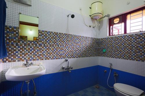 a blue and white bathroom with a sink and a toilet at Skylarc Inn in Ooty