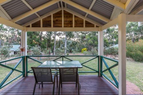 a patio with a table and chairs on a deck at Bushy Lake Chalets in Margaret River Town