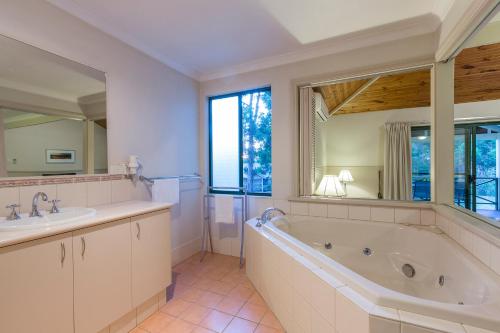 a bathroom with a tub and a sink and a large mirror at Bushy Lake Chalets in Margaret River Town