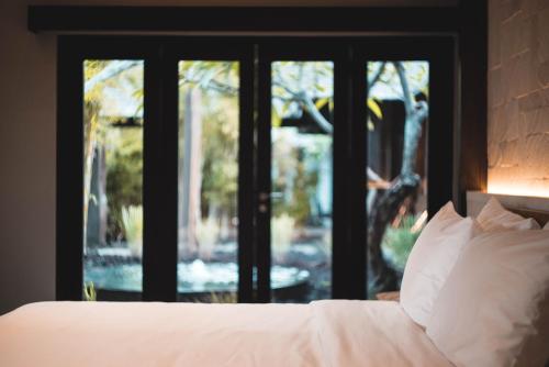 a bed with white sheets and pillows in front of a window at The Istana in Uluwatu