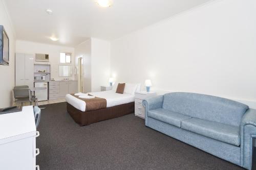 a hotel room with a bed, couch and a television at Carrum Downs Motel in Carrum Downs