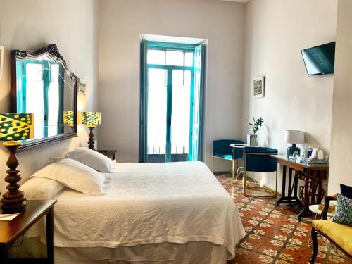 a bedroom with a bed, a desk and a window at Hotel Boutique Casa de Colón in Seville
