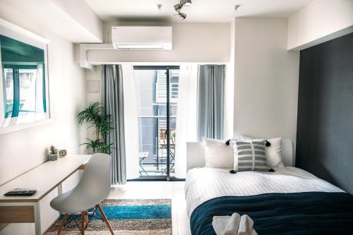 Un dormitorio con una cama y un escritorio y una ventana. en Dash Living Nihonbashi, en Tokio