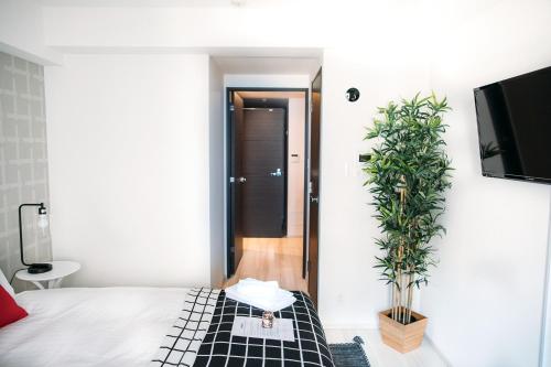 - une chambre avec un lit et une plante en pot dans l'établissement Dash Living Nihonbashi, à Tokyo