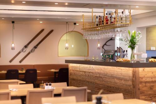 a restaurant with a bar with white tables and chairs at Hotel Goldried in Matrei in Osttirol