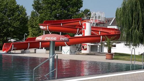 a red water slide next to a pool of water at Hotel am See Rust in Rust