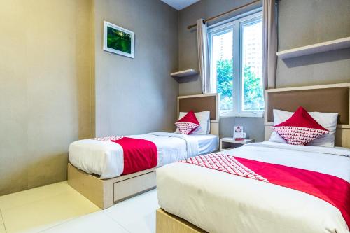 a bedroom with two beds and a window at OYO 279 Deli Homestay in Medan