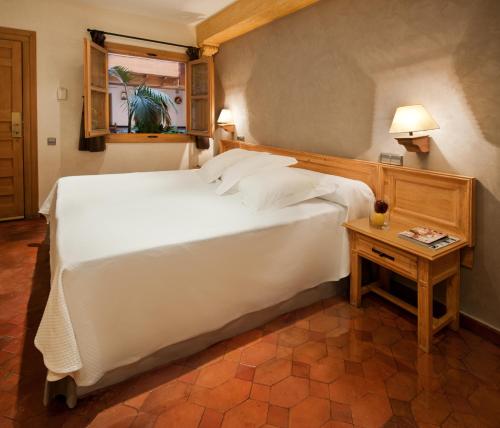 a bedroom with a large white bed and a table at Hotel Pintor El Greco in Toledo