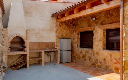 a kitchen with a refrigerator and a stone wall at Casa Turistica Rivera Del Zurguen in Morille