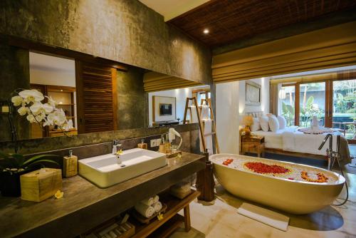 un bagno con vasca, lavandino e letto di Purana Suite Ubud ad Ubud