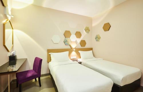 um quarto de hotel com duas camas e uma cadeira roxa em ibis budget Singapore Imperial em Singapura