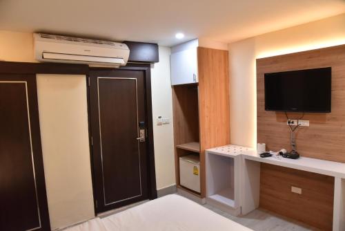 a hotel room with a television and a door with a desk at Rose Nana Hotel in Bangkok