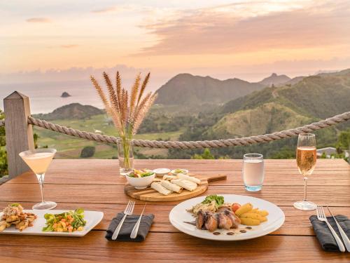 a table with two plates of food and glasses of wine at Selong Selo Resort and Residences in Selong Belanak