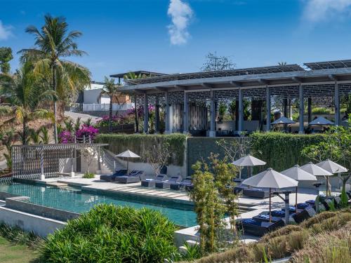 un complexe avec une piscine, des chaises et des parasols dans l'établissement Selong Selo Resort and Residences, à Selong Belanak