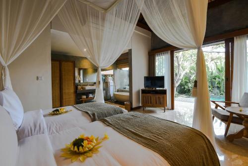a bedroom with two beds and a television in a room at Purana Suite Ubud in Ubud
