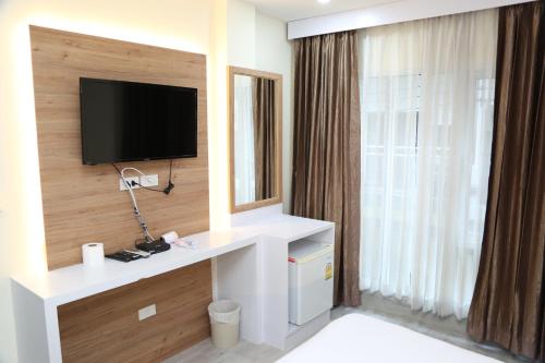 a hotel room with a tv and a large window at Rose Nana Hotel in Bangkok