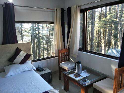 a bedroom with a bed and a chair and a window at Rock resort in Dhanaulti