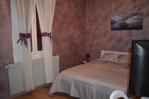 a bedroom with a bed and a window and a television at Chez Augustin in Lacanau-Océan