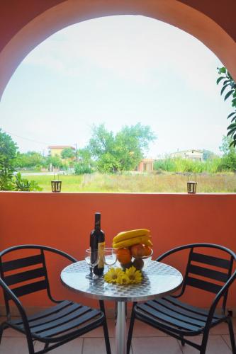 a table with fruit and a bottle of wine and two chairs at XIDIS in Laganas